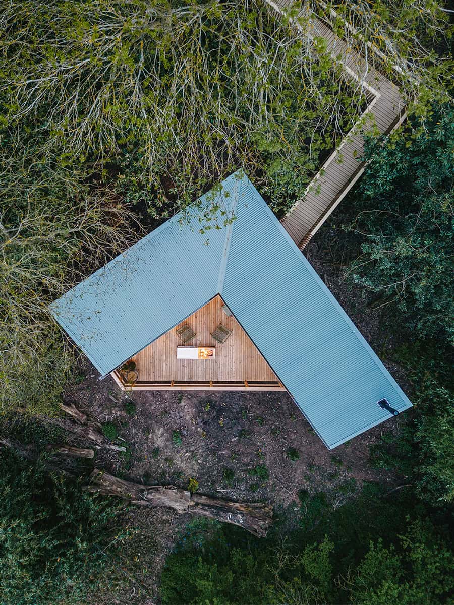 Aerial view of Elmore Treehouses eco-lodge with timber deck nestled in woodland canopy, Gloucestershire